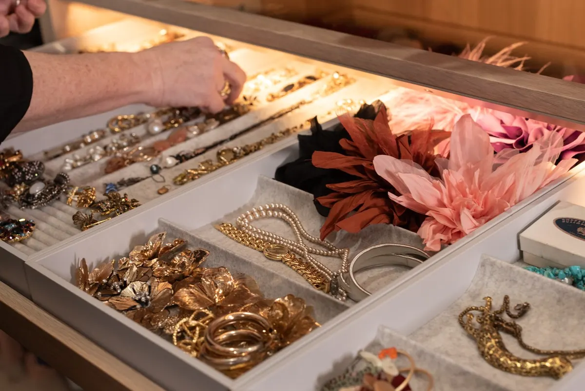An open drawer of gold jewellery, pearls and silk flower corsages
