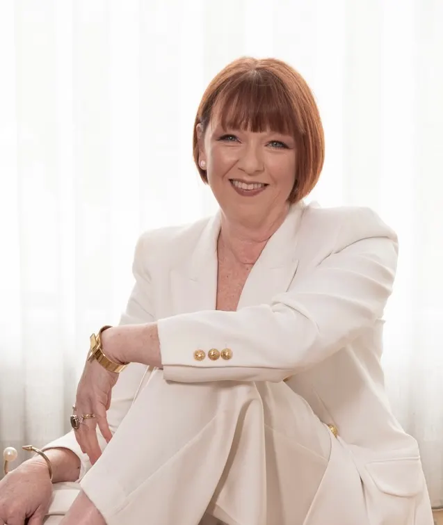Steph seated in a cream suit, smiling warmly