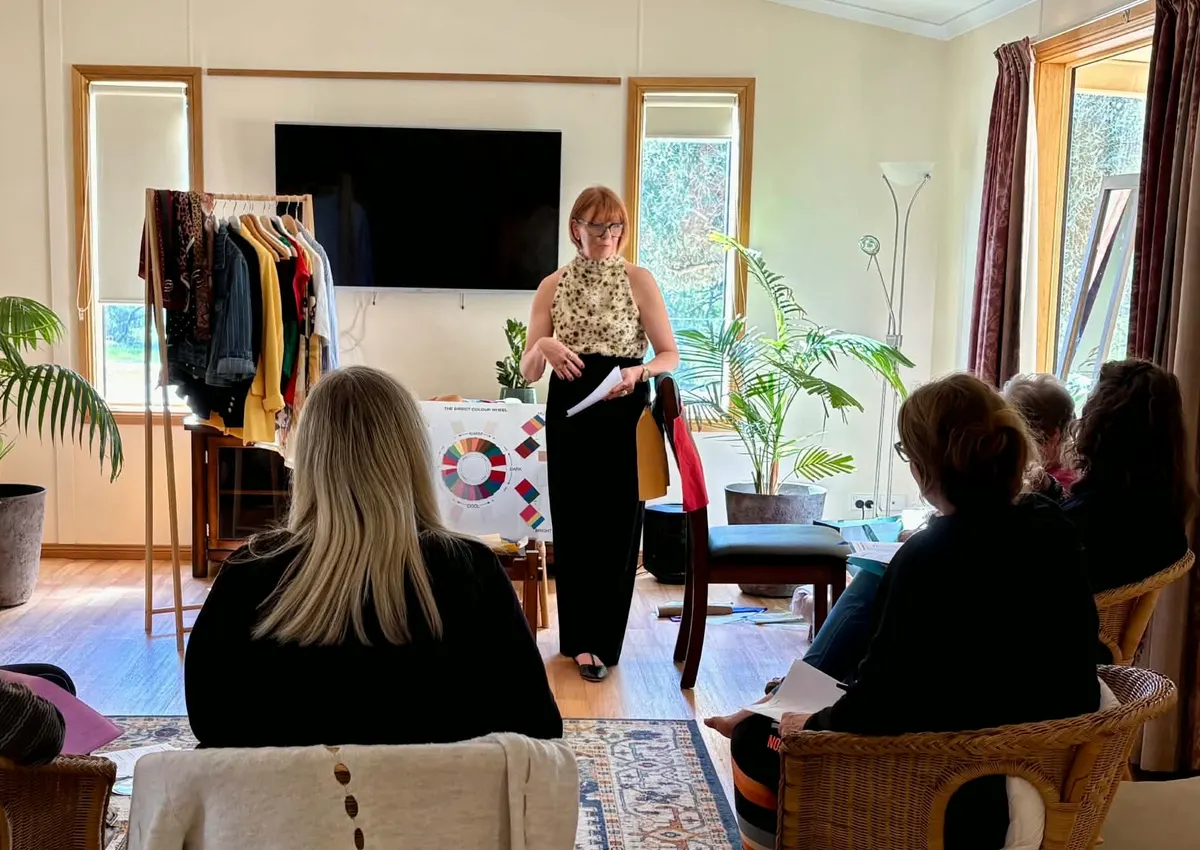 Steph presenting a colour workshop to a group of women, beside a clothing rail and colour wheel
